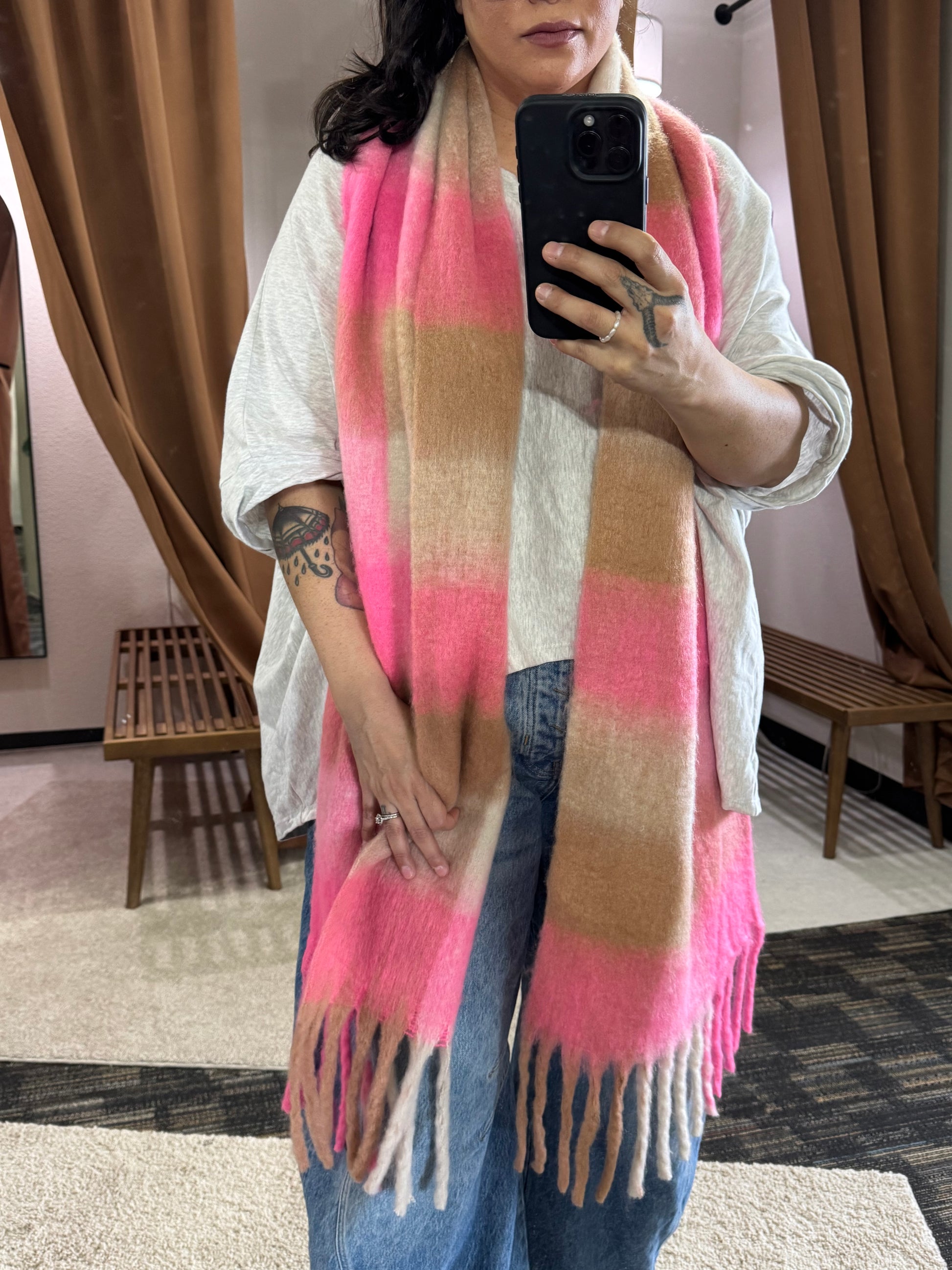 Showcasing a wide and long scarf that has multi color pattern featuring bright pink, beige, and cream. It’s a bold choice for spring but the neutral colors make it so approachable and casual to wear. 