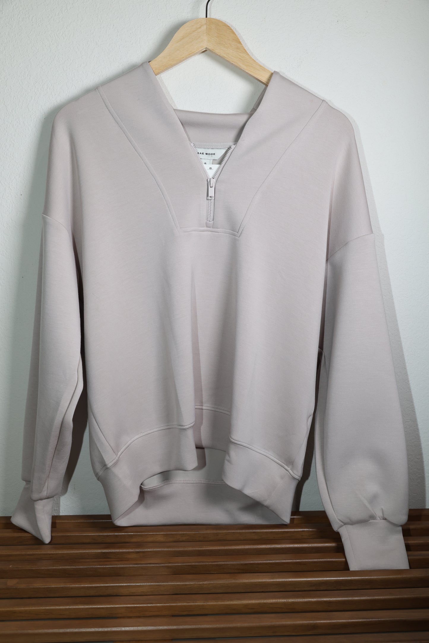 Light beige long sleeve top with half zipper front against a white background