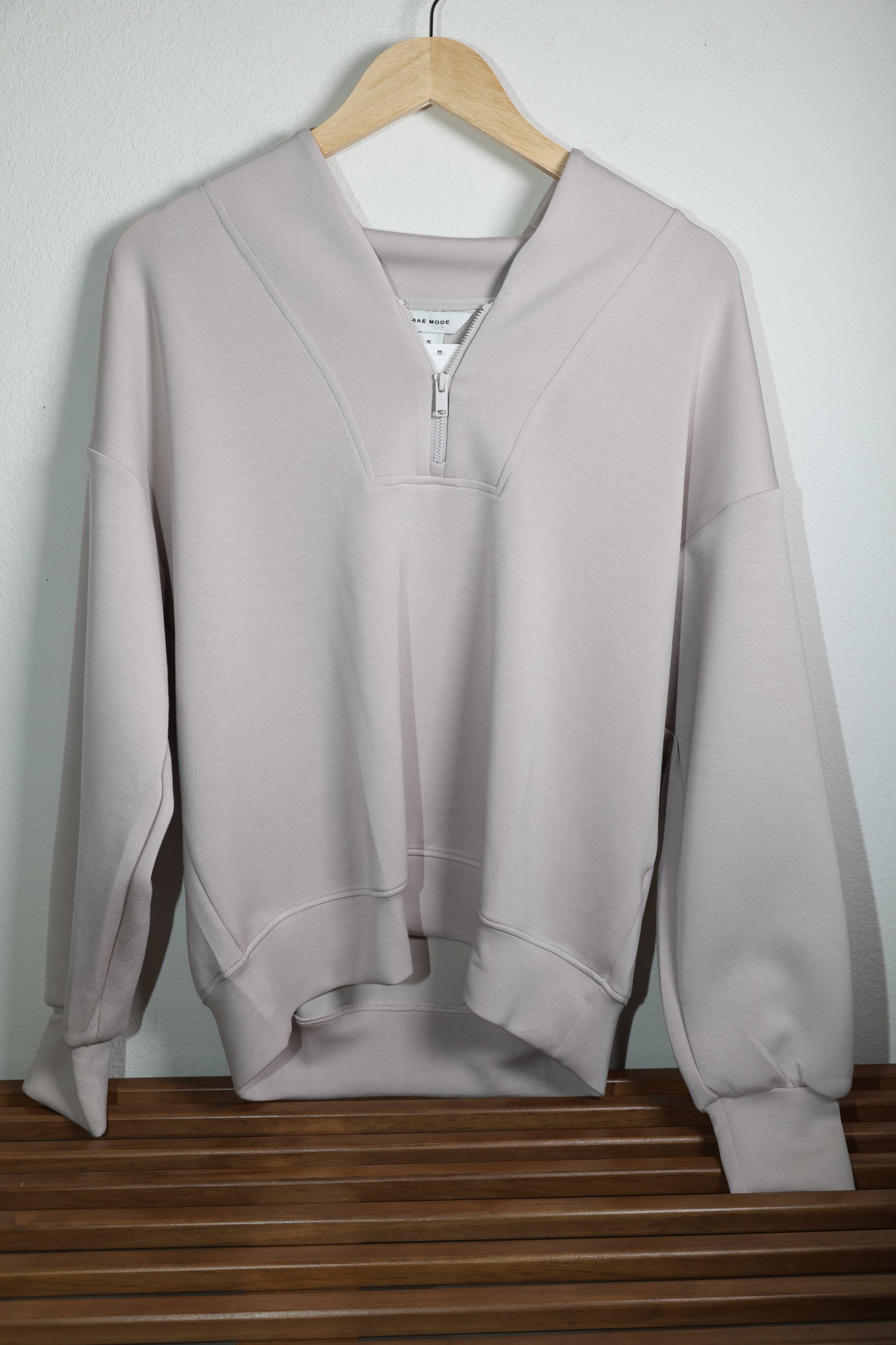 Light beige long sleeve top with half zipper front against a white background