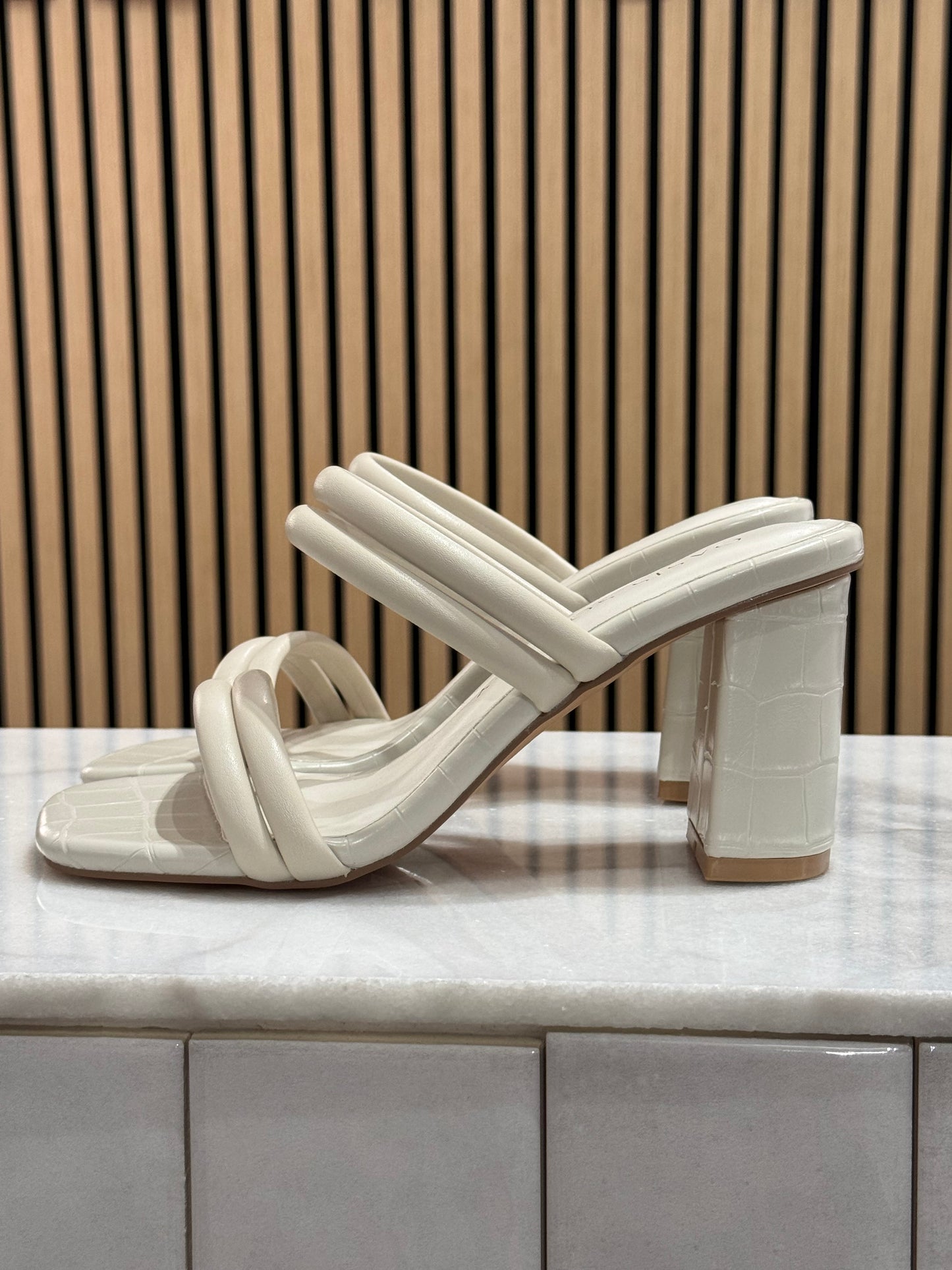 Modern strappy chunky block square heel. These have a puffy double strap across the toes and across the middle of foot making this a modern sleek finish. The cream color is perfect for graduation season and the material overall has a faux alligator imprint look to it. 