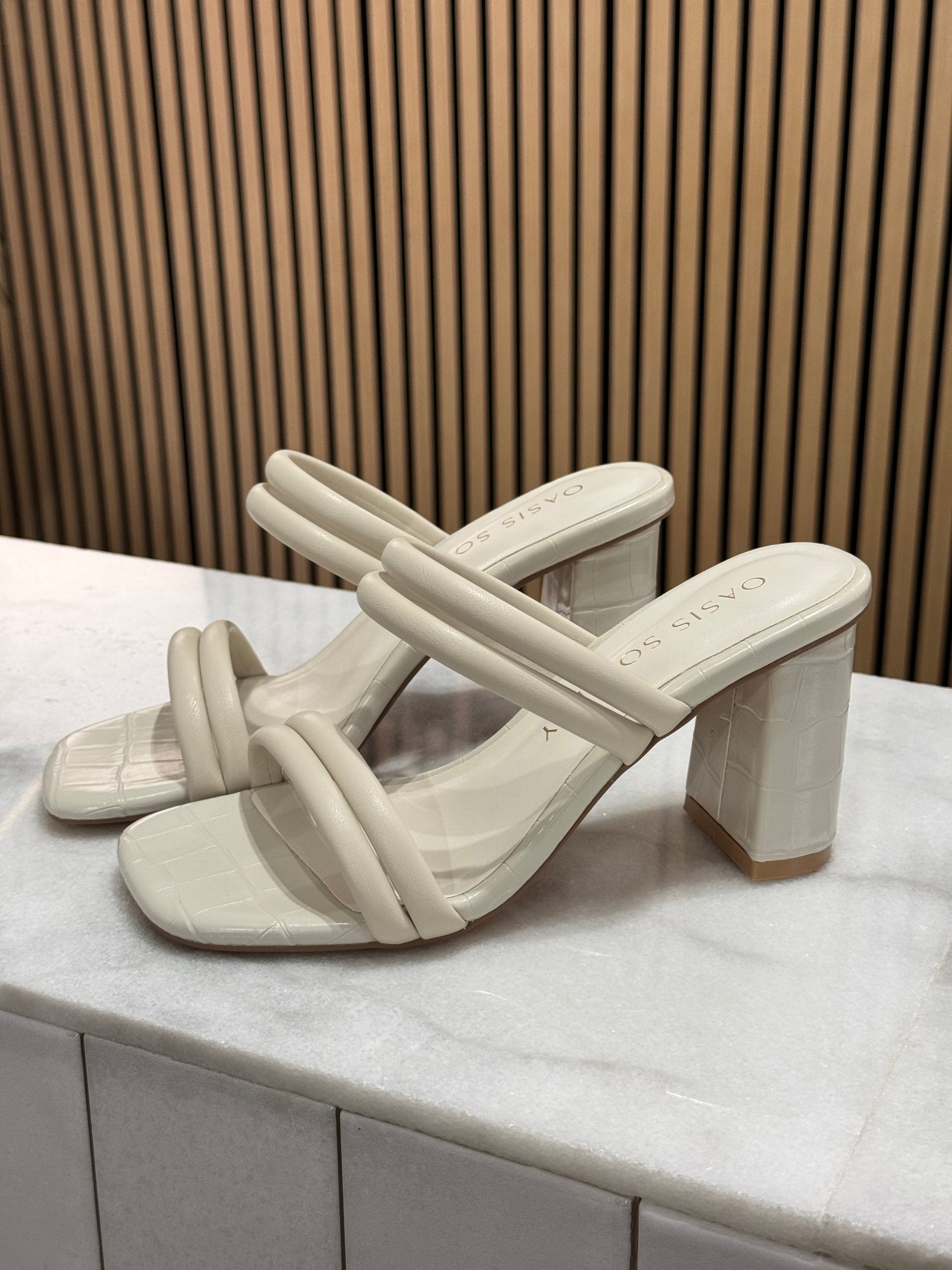 Modern strappy chunky block square heel. These have a puffy double strap across the toes and across the middle of foot making this a modern sleek finish. The cream color is perfect for graduation season and the material overall has a faux alligator imprint look to it. 