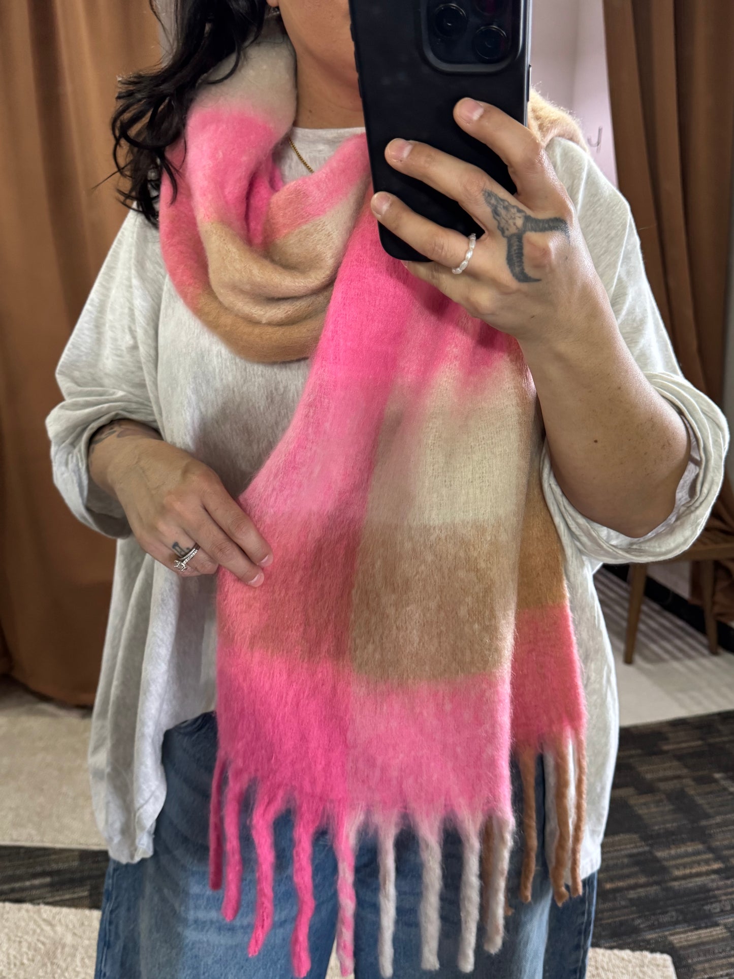 Showcasing a wide and long scarf that has multi color pattern featuring bright pink, beige, and cream. It’s a bold choice for spring but the neutral colors make it so approachable and casual to wear. 