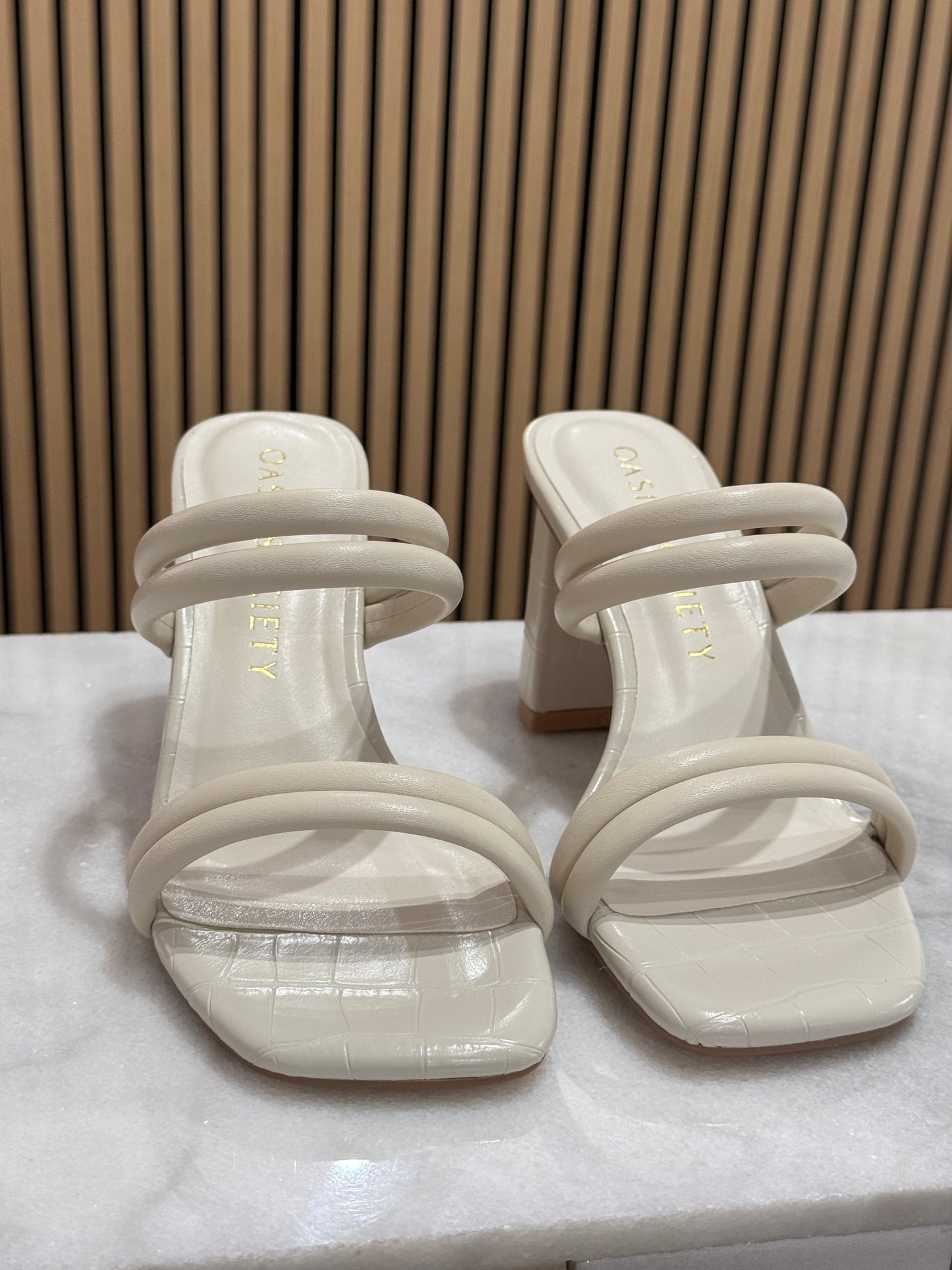 Modern strappy chunky block square heel. These have a puffy double strap across the toes and across the middle of foot making this a modern sleek finish. The cream color is perfect for graduation season and the material overall has a faux alligator imprint look to it. 
