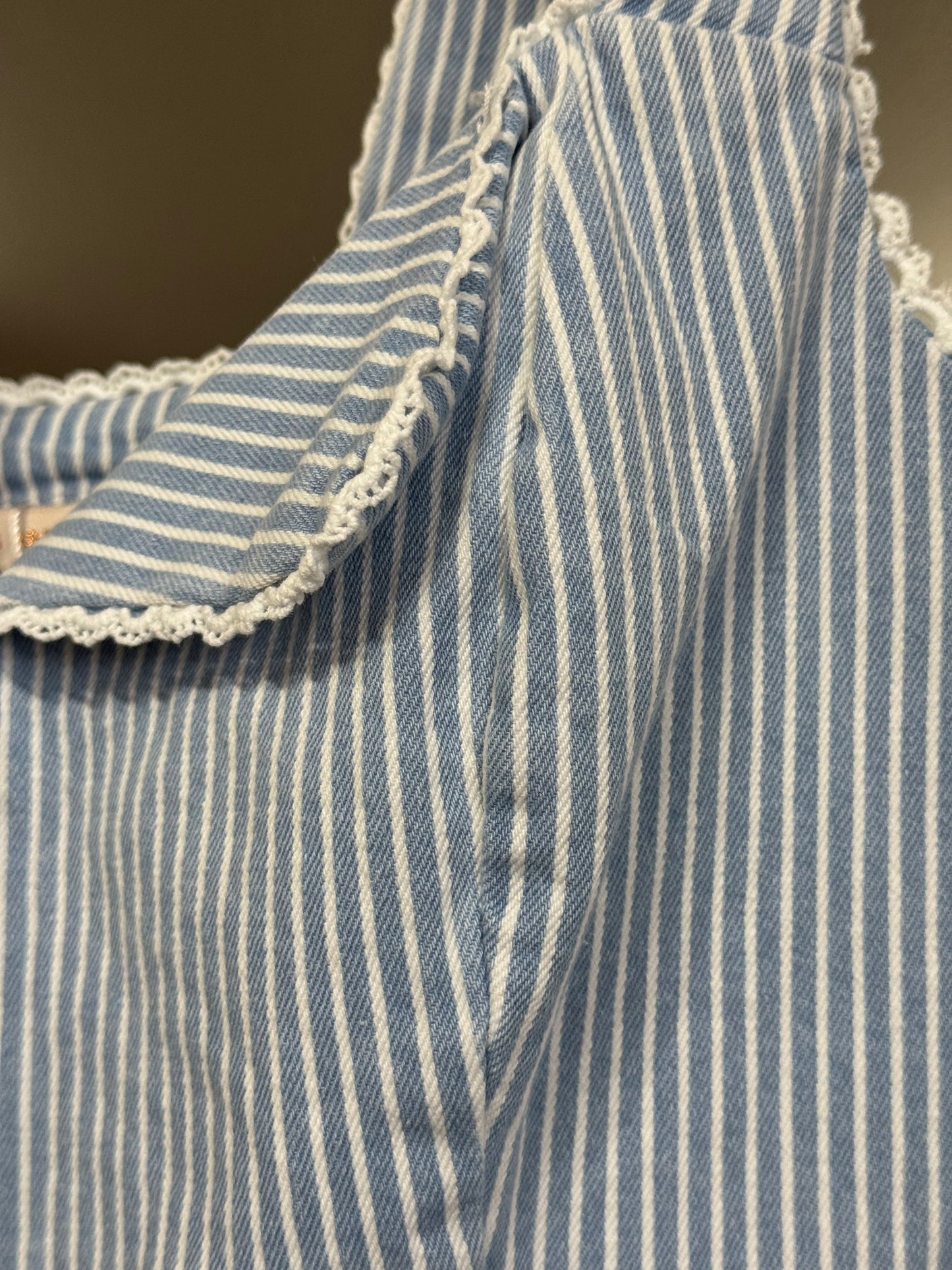 A closer look at the Stripe fitted button front corset like top featuring lace trim edge and thin light blue and white pinstripes. 