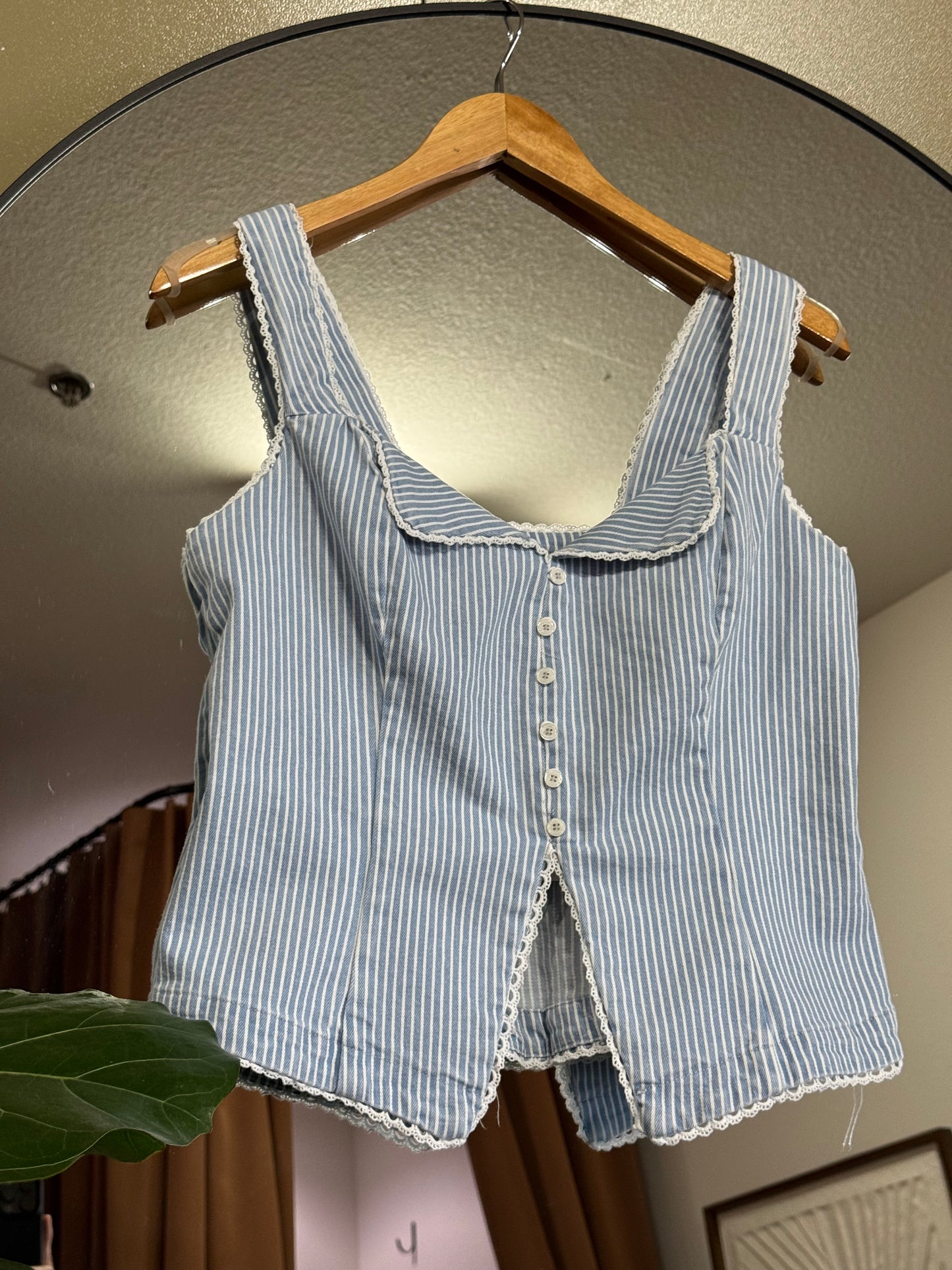 Stripe fitted button front corset like top featuring lace trim edge and thin light blue and white pinstripes. 