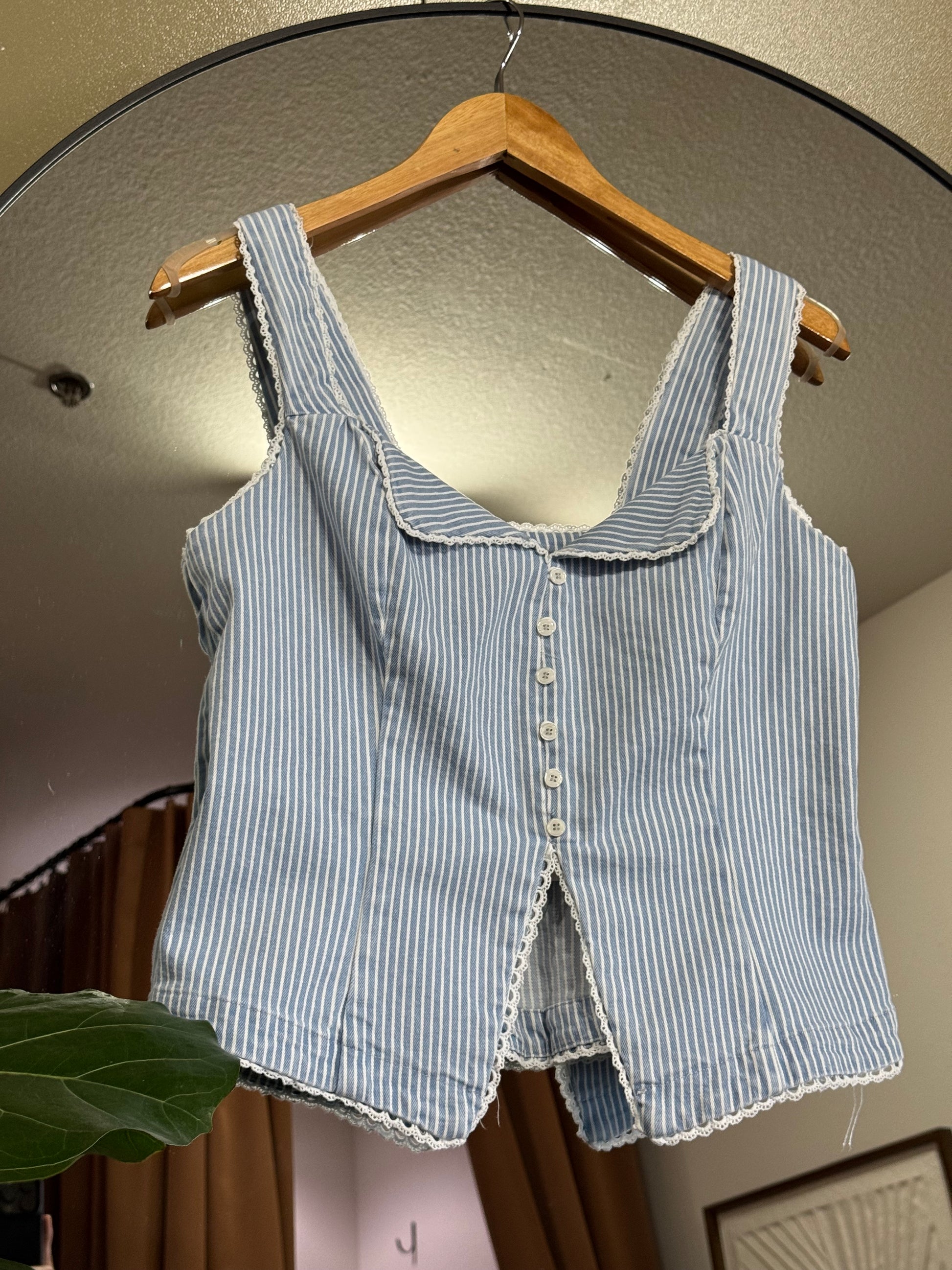 Stripe fitted button front corset like top featuring lace trim edge and thin light blue and white pinstripes. 