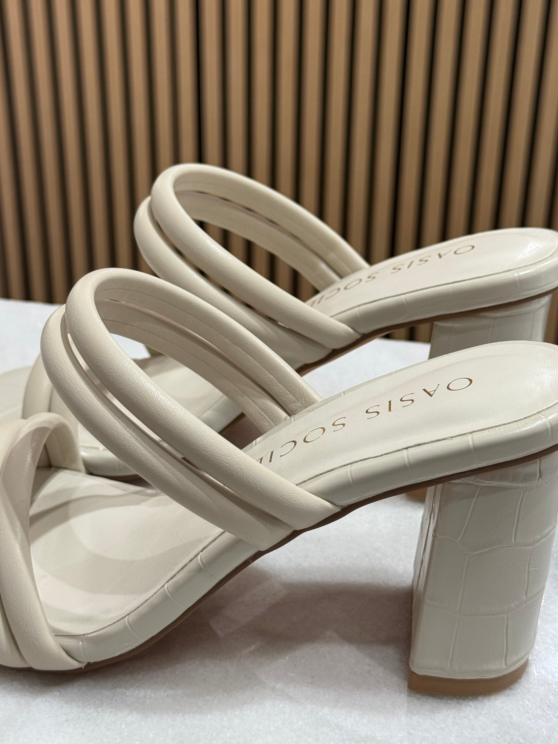Modern strappy chunky block square heel. These have a puffy double strap across the toes and across the middle of foot making this a modern sleek finish. The cream color is perfect for graduation season and the material overall has a faux alligator imprint look to it. 